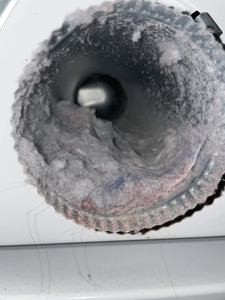 Close-up of a dryer vent tube showing lint buildup and potential fire hazard.
