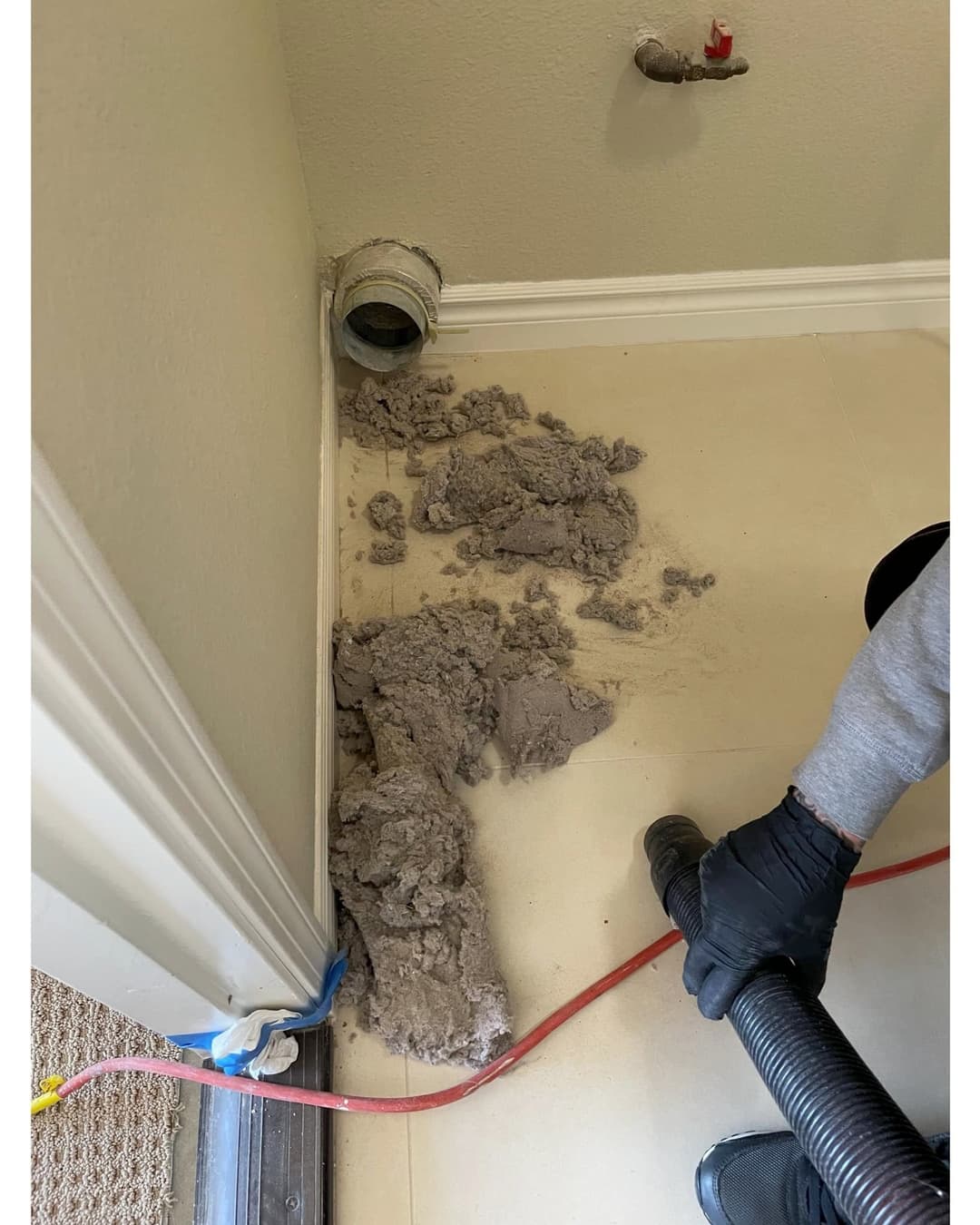 Drywall debris and dust being vacuumed near a vent in a residential room.