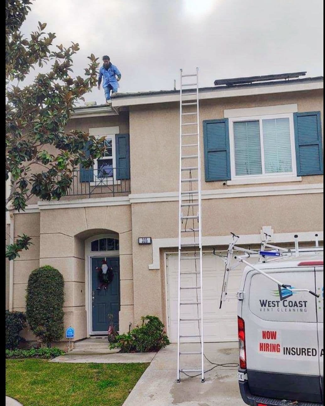 Worker cleaning roof gutters with ladder beside residential home, West Coast Vent Cleaning van visible.